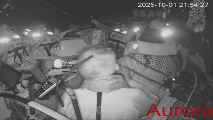 <i>لقطة شاشة من فيديو مباشر تُظهر أفراد الطاقم جالسين على متن سفينة أورورا المتجهة إلى غزة</i><br>