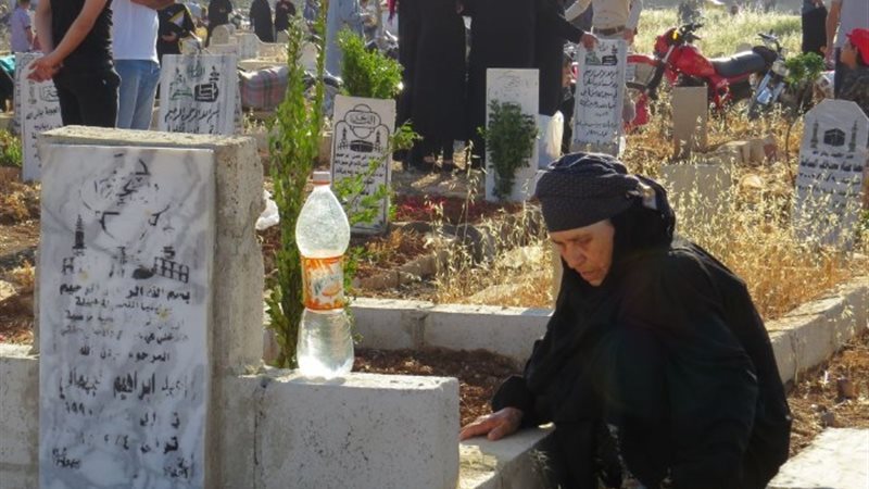 سيدة تمكث بجوار قبر